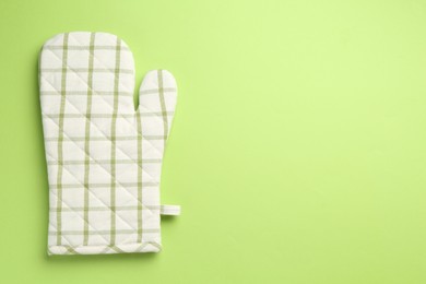 Photo of One oven glove on green background, top view. Space for text