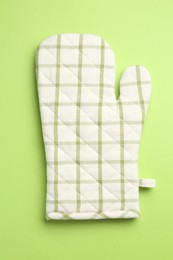 Photo of One oven glove on green background, top view