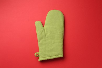 Photo of One oven glove on red background, top view