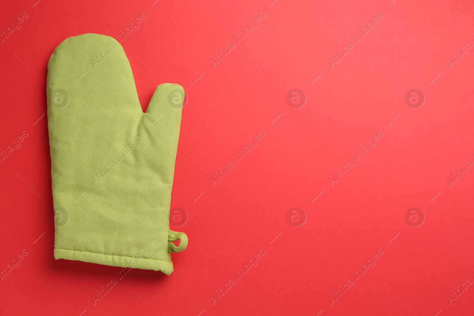 Photo of One oven glove on red background, top view. Space for text