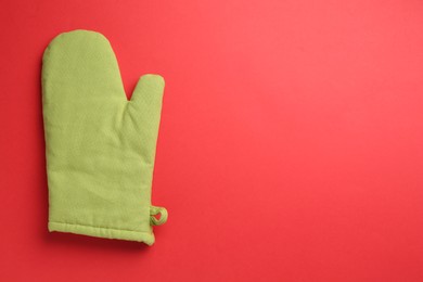 Photo of One oven glove on red background, top view. Space for text