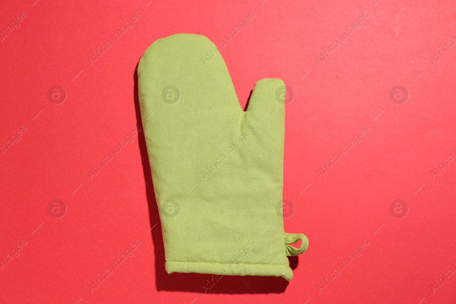 One oven glove on red background, top view Photo of One oven glove on red background, top view