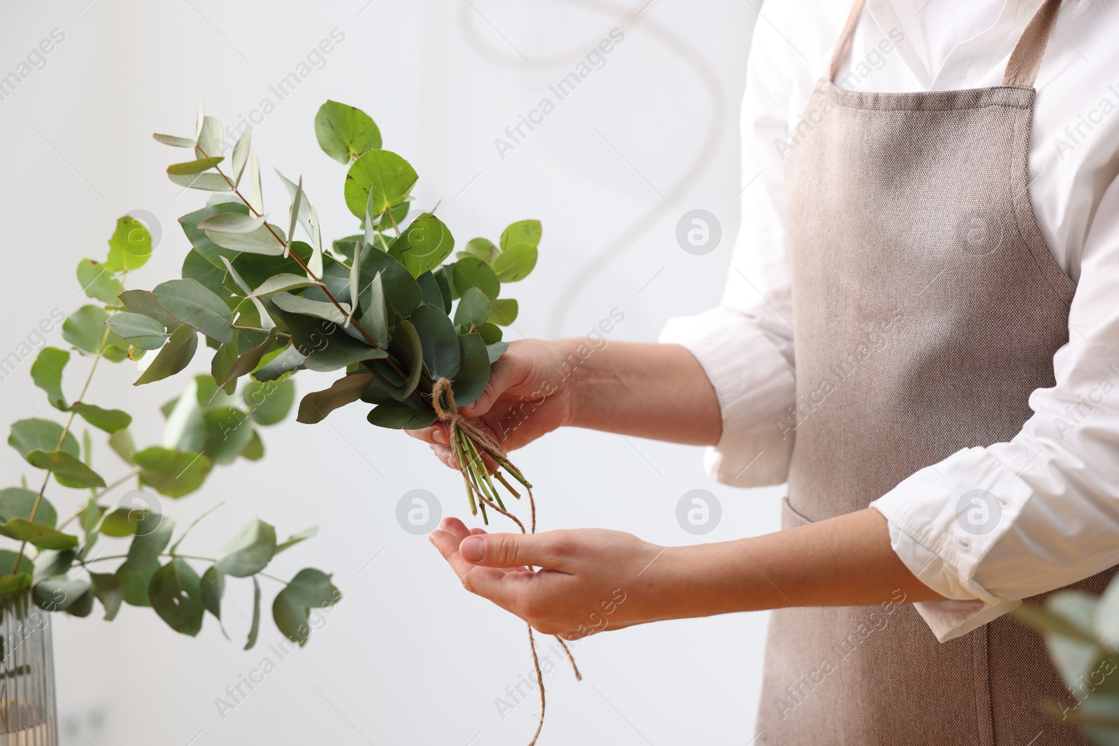Florist making beautiful bouquet of eucalyptus branches in flower shop, closeup Photo of Florist making beautiful bouquet of eucalyptus branches in flower shop, closeup