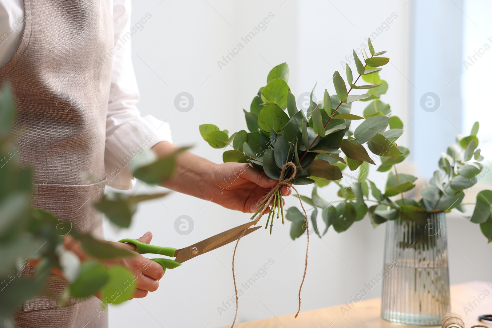 Florist making beautiful bouquet of eucalyptus branches in flower shop, closeup Photo of Florist making beautiful bouquet of eucalyptus branches in flower shop, closeup