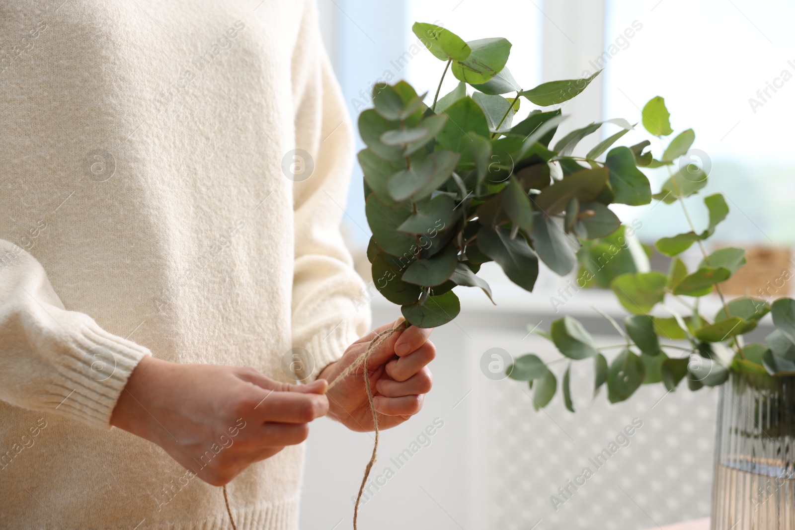 Florist making beautiful bouquet of eucalyptus branches in flower shop, closeup Photo of Florist making beautiful bouquet of eucalyptus branches in flower shop, closeup