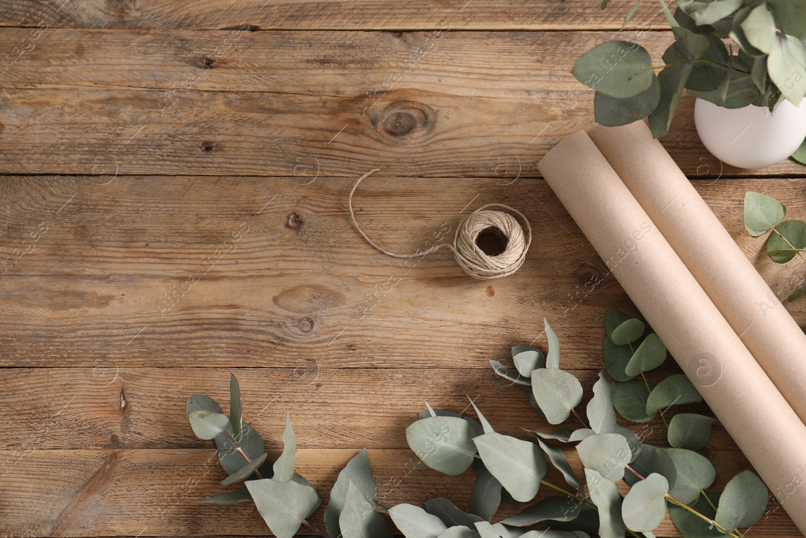 Florist. Eucalyptus branches, thread and wrapping paper on wooden table, flat lay. Space for text Photo of Florist. Eucalyptus branches, thread and wrapping paper on wooden table, flat lay. Space for text