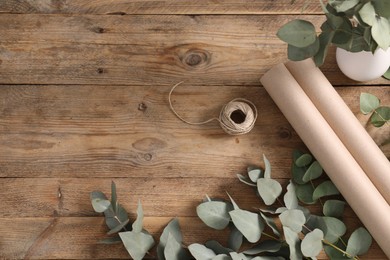 Photo of Florist. Eucalyptus branches, thread and wrapping paper on wooden table, flat lay. Space for text