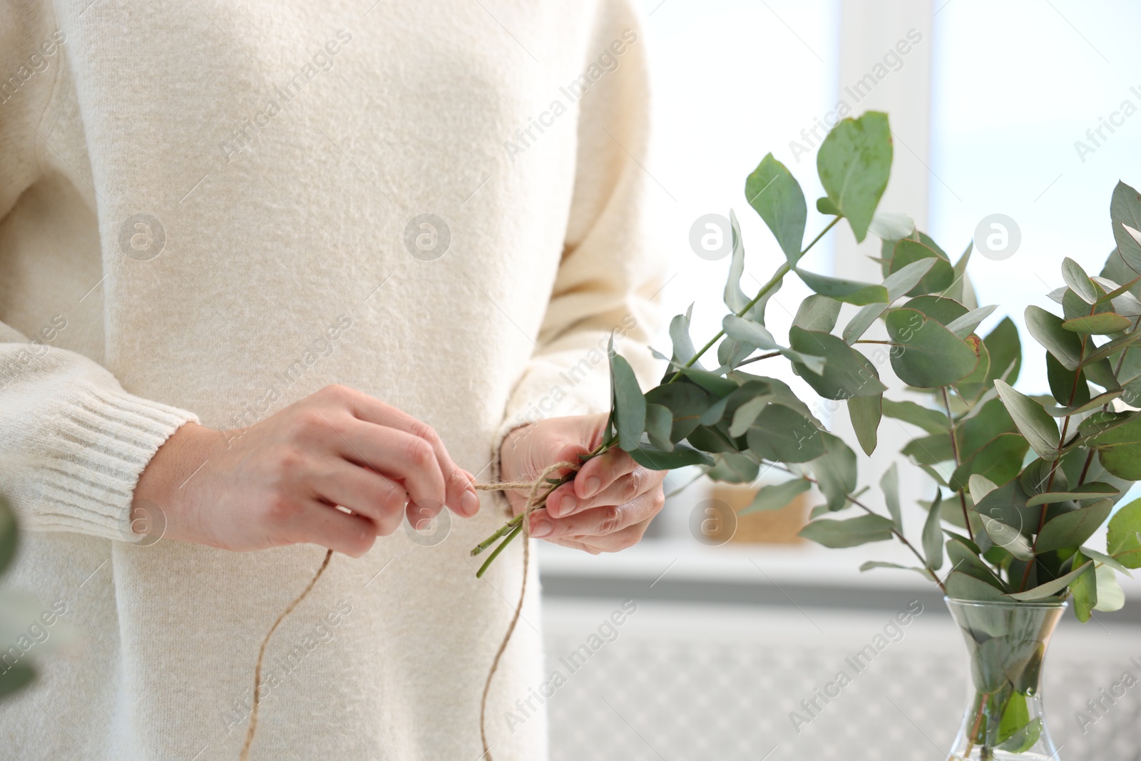 Florist making beautiful bouquet of eucalyptus branches in flower shop, closeup Photo of Florist making beautiful bouquet of eucalyptus branches in flower shop, closeup