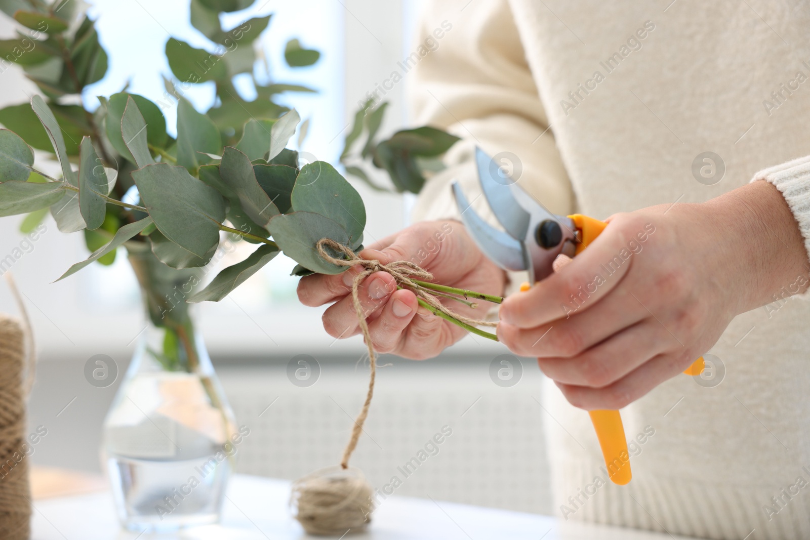 Photo of Florist making beautiful bouquet of eucalyptus branches at table in flower shop, closeup