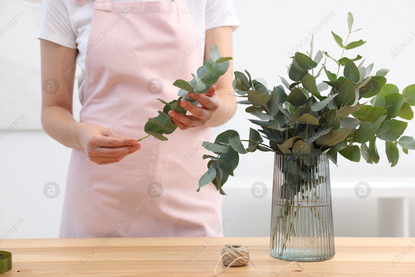 Florist making beautiful bouquet of eucalyptus branches at wooden table in flower shop, closeup Photo of Florist making beautiful bouquet of eucalyptus branches at wooden table in flower shop, closeup