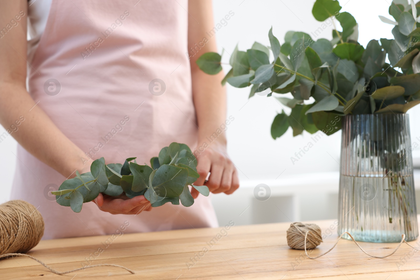 Florist making beautiful bouquet of eucalyptus branches at wooden table in flower shop, closeup Photo of Florist making beautiful bouquet of eucalyptus branches at wooden table in flower shop, closeup