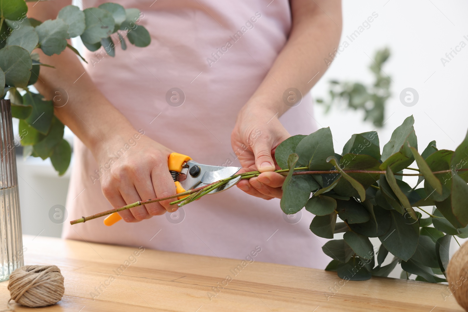 Florist making beautiful bouquet of eucalyptus branches at wooden table in flower shop, closeup Photo of Florist making beautiful bouquet of eucalyptus branches at wooden table in flower shop, closeup