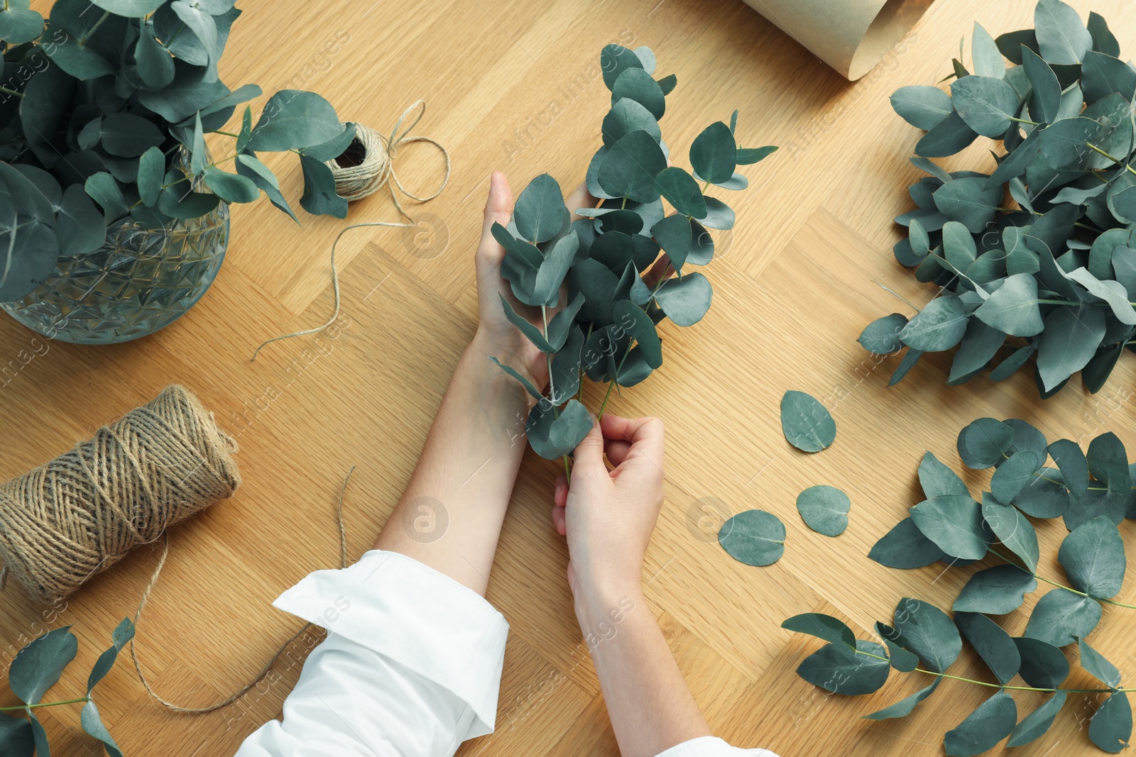Florist making beautiful bouquet of eucalyptus branches at wooden table, top view Photo of Florist making beautiful bouquet of eucalyptus branches at wooden table, top view