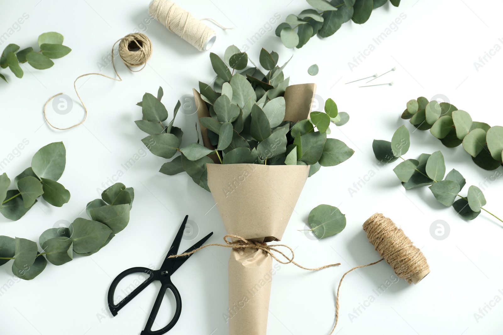 Florist. Eucalyptus branches, threads and scissors on white table, flat lay Photo of Florist. Eucalyptus branches, threads and scissors on white table, flat lay