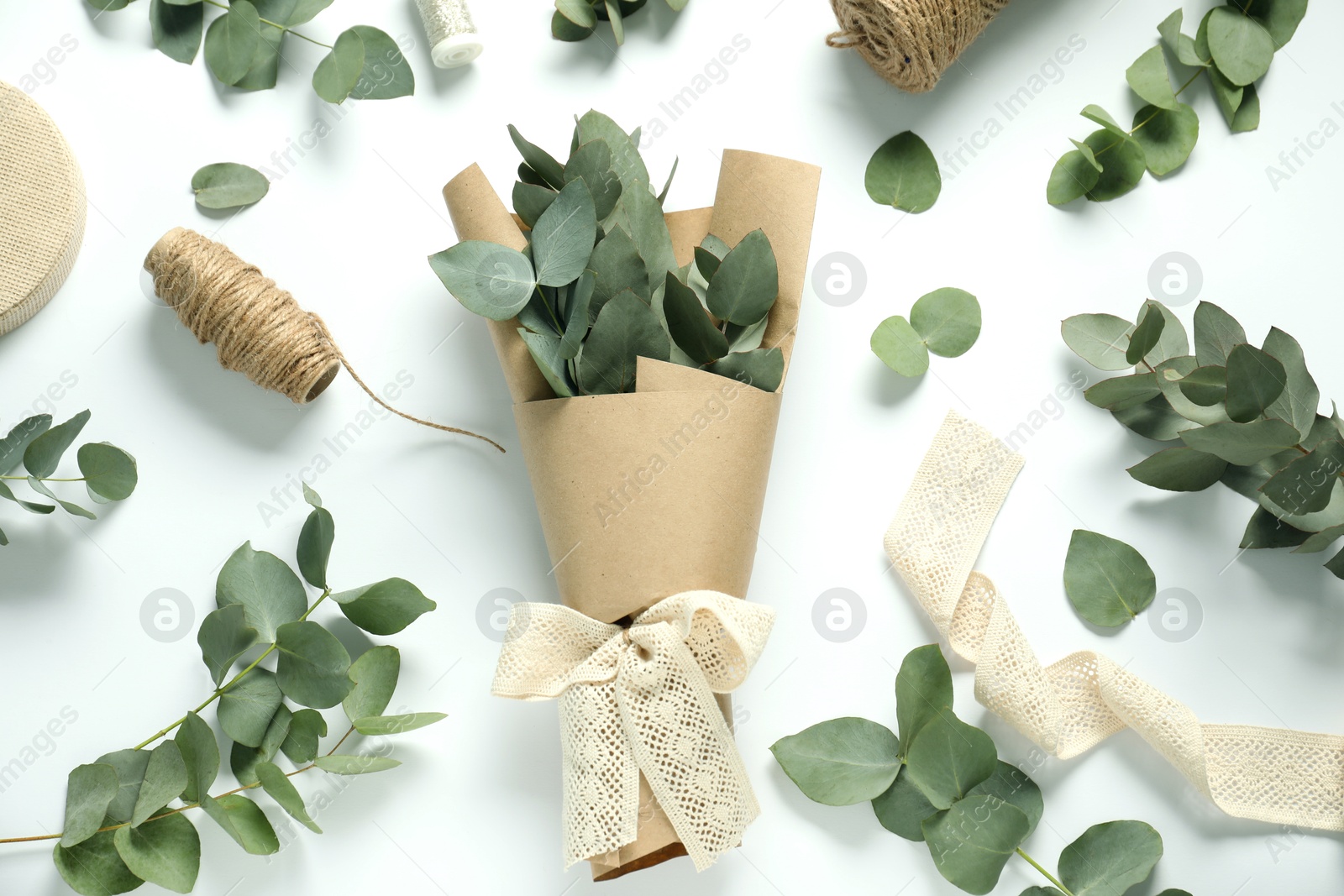 Florist. Eucalyptus branches, threads, ribbon and wrapping paper on white table, flat lay Photo of Florist. Eucalyptus branches, threads, ribbon and wrapping paper on white table, flat lay