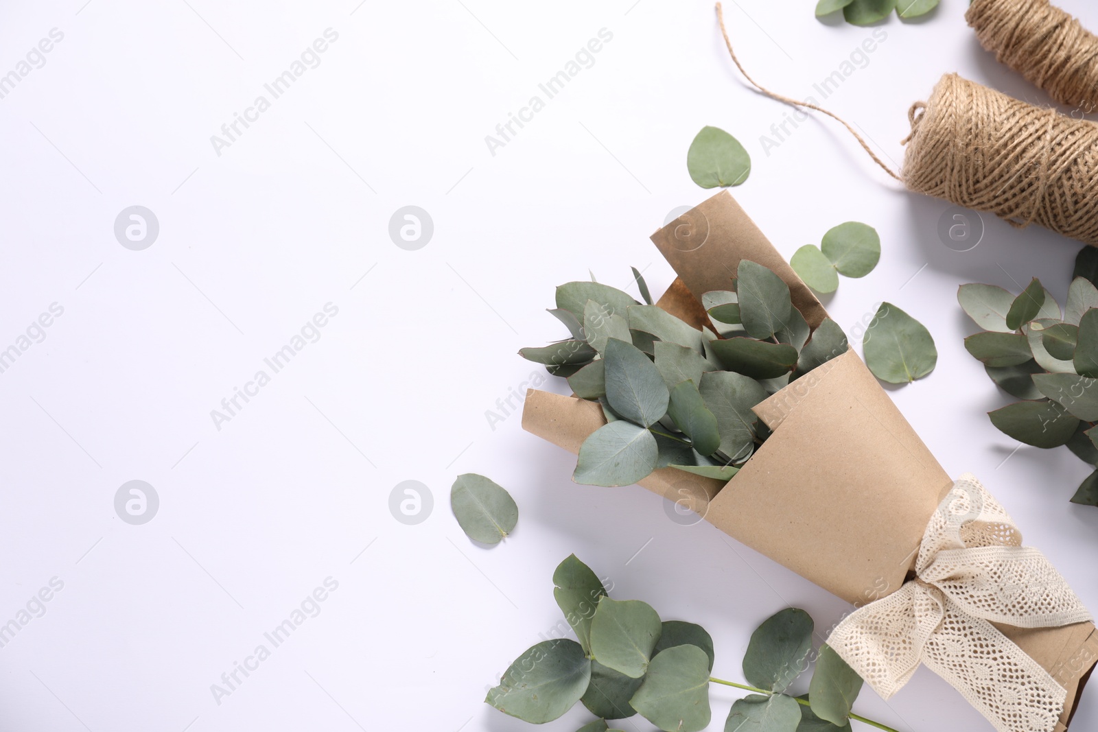 Florist. Eucalyptus branches and threads on white table, flat lay. Space for text Photo of Florist. Eucalyptus branches and threads on white table, flat lay. Space for text