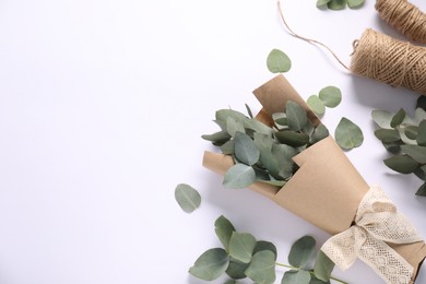 Photo of Florist. Eucalyptus branches and threads on white table, flat lay. Space for text