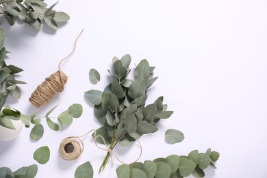 Photo of Florist. Eucalyptus branches and threads on white table, flat lay. Space for text