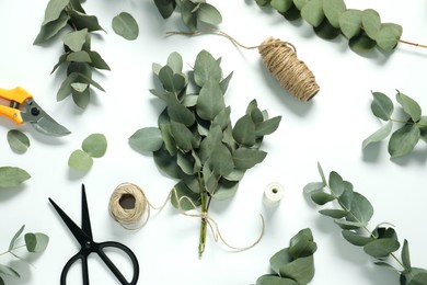 Photo of Florist. Eucalyptus branches, threads, scissors and pruner on white table, flat lay