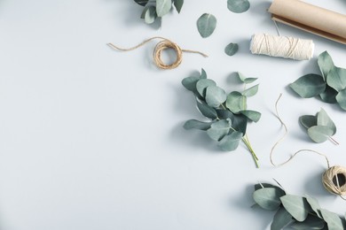 Photo of Florist. Eucalyptus branches, threads and wrapping paper on white table, flat lay. Space for text