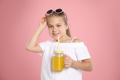 Photo of Little girl with juice and drinking straw on pink background