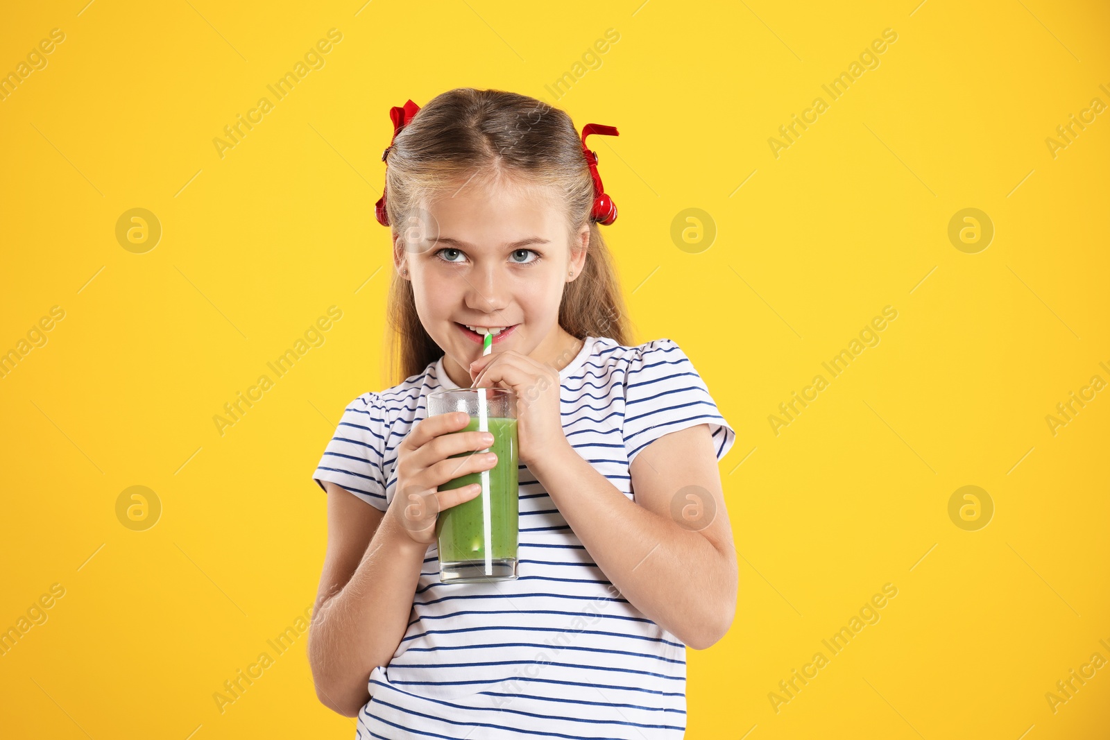 Photo of Little girl drinking juice through straw on orange background