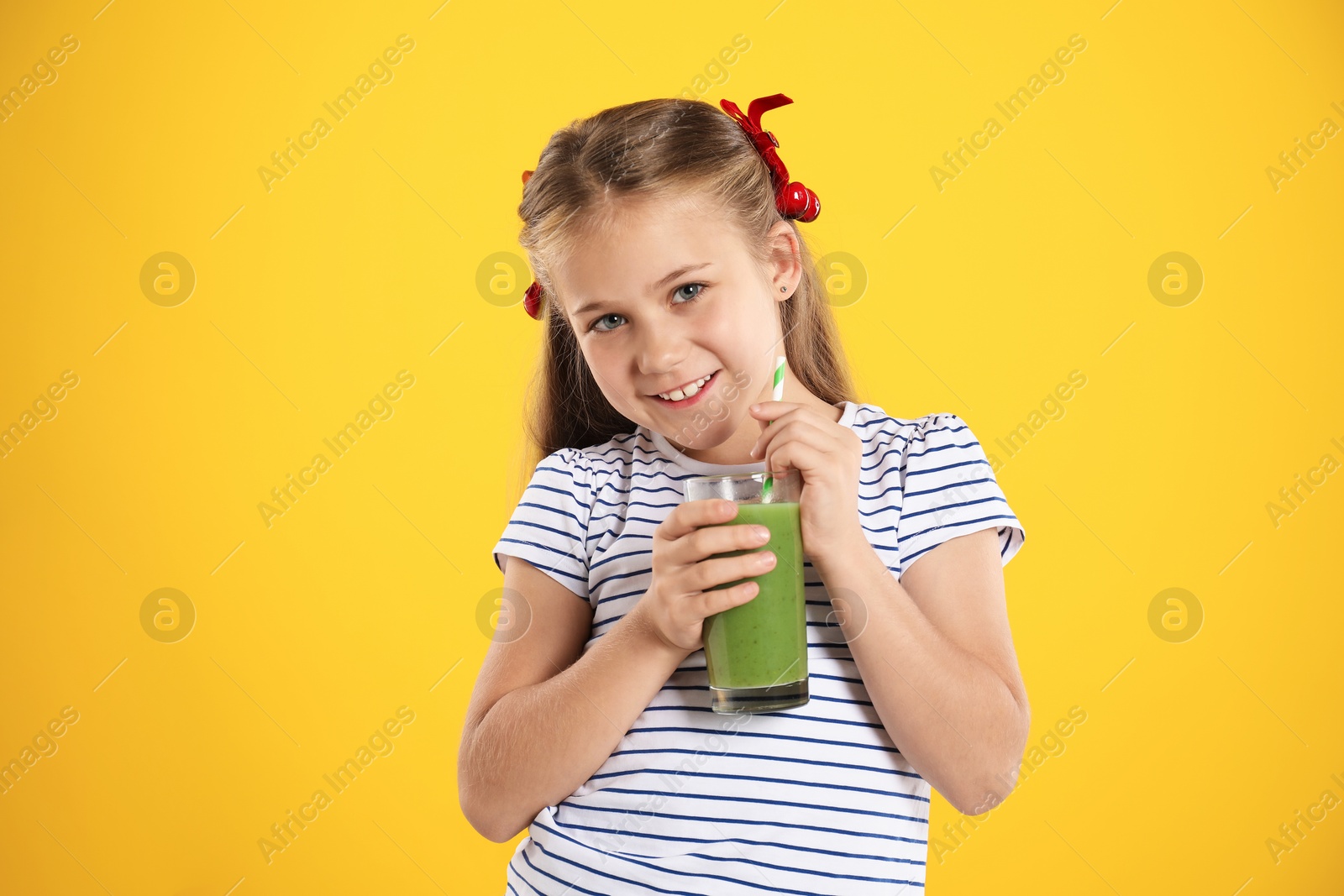 Photo of Little girl with juice and drinking straw on orange background