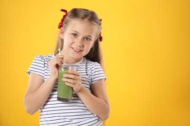 Photo of Little girl with juice and drinking straw on orange background, space for text