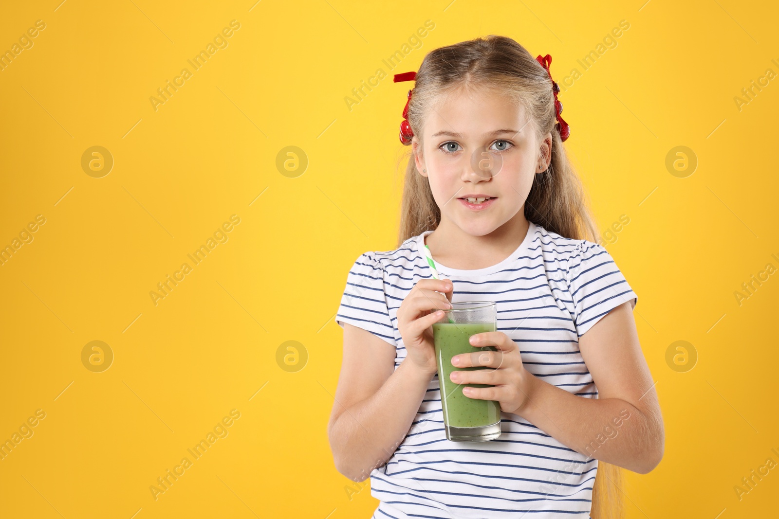 Photo of Little girl with juice and drinking straw on orange background, space for text