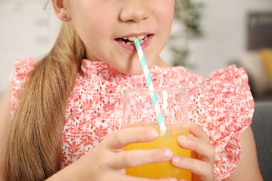 Photo of Little girl drinking juice through straw at home, closeup