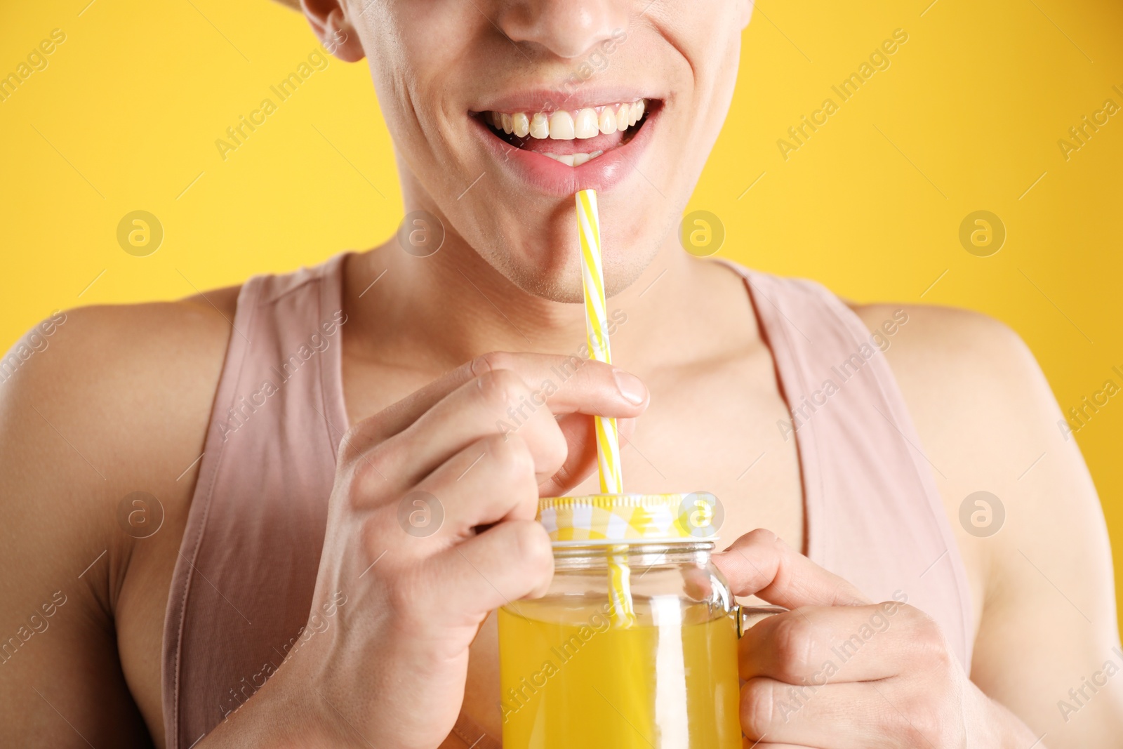 Photo of Man with juice and drinking straw on orange background, closeup
