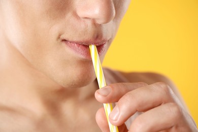 Photo of Man with drinking straw on orange background, closeup