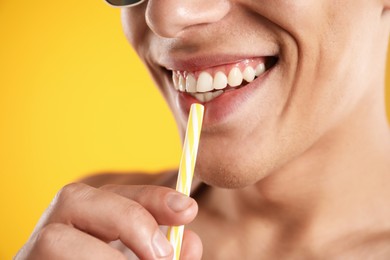 Photo of Man with drinking straw on orange background, closeup