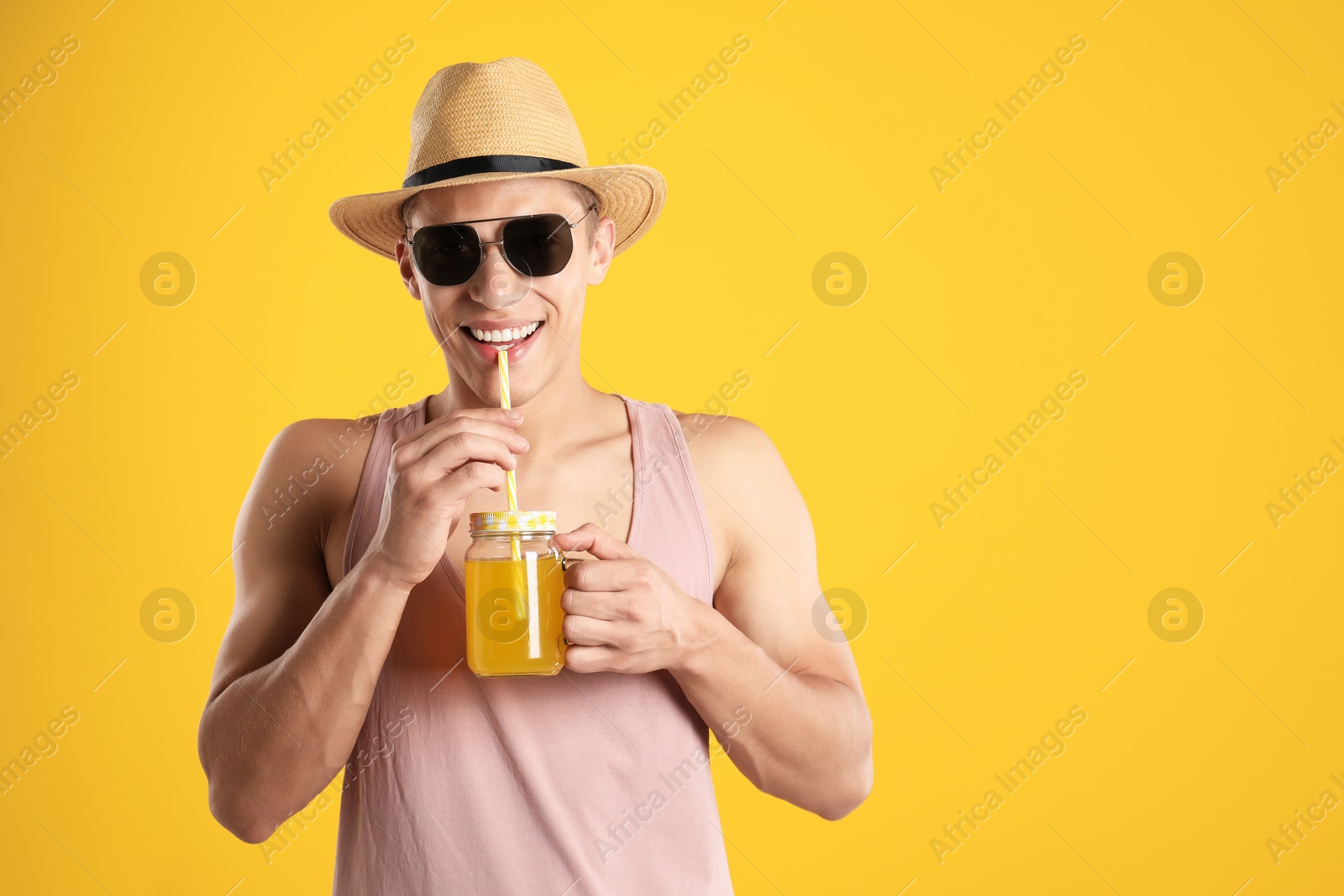 Photo of Man with juice and drinking straw on orange background, space for text