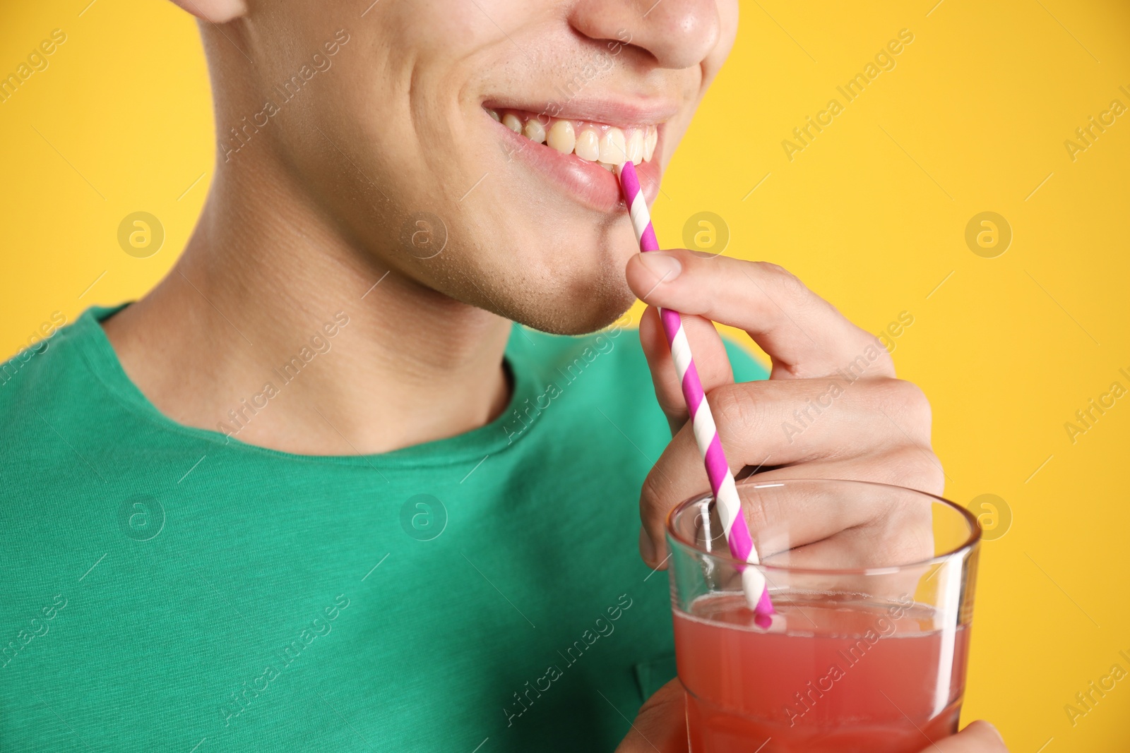Photo of Man with juice and drinking straw on orange background, closeup