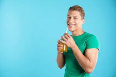 Photo of Man with juice and drinking straw on light blue background, space for text