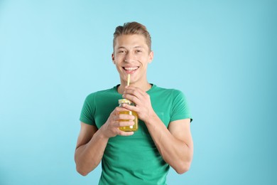 Photo of Man with juice and drinking straw on light blue background