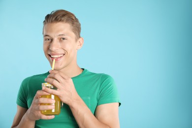 Photo of Man with juice and drinking straw on light blue background, space for text