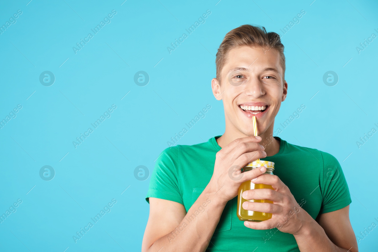 Photo of Man with juice and drinking straw on light blue background, space for text