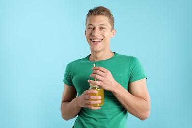 Photo of Man with juice and drinking straw on light blue background