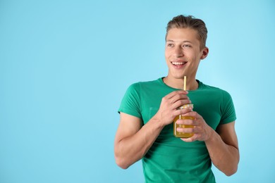 Photo of Man with juice and drinking straw on light blue background, space for text