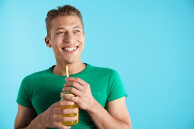 Photo of Man with juice and drinking straw on light blue background, space for text