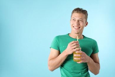 Photo of Man with juice and drinking straw on light blue background, space for text