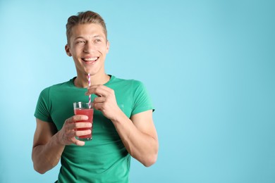 Photo of Man with juice and drinking straw on light blue background, space for text