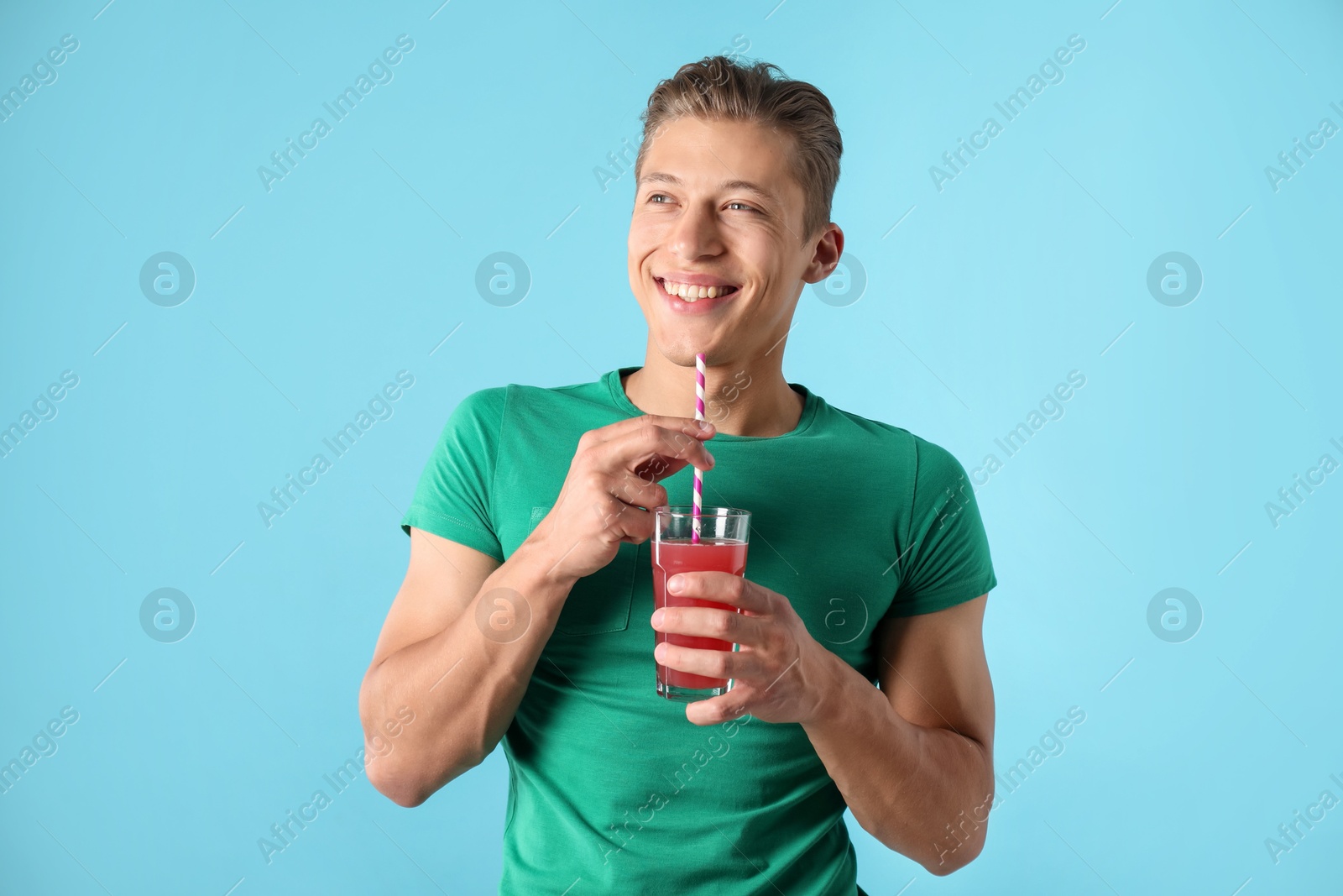 Photo of Man with juice and drinking straw on light blue background
