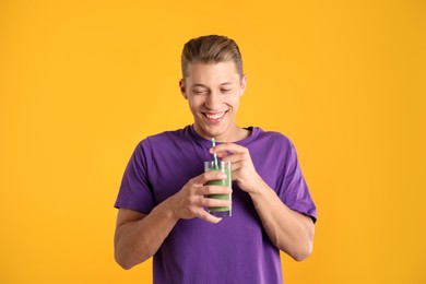 Photo of Man with juice and drinking straw on orange background