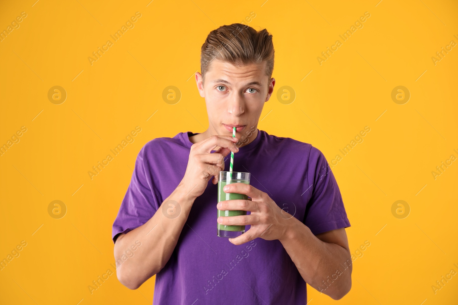 Photo of Man drinking juice through straw on orange background