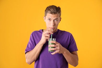 Photo of Man drinking juice through straw on orange background