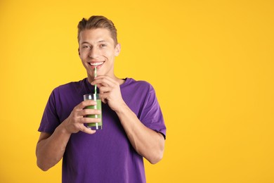 Photo of Man drinking juice through straw on orange background, space for text