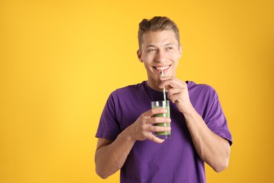 Photo of Man drinking juice through straw on orange background, space for text